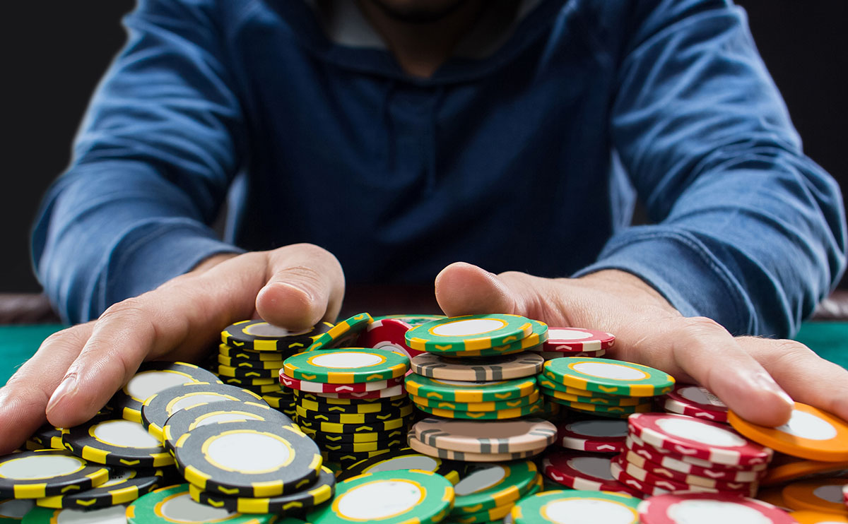 Jugador arrastrando una gran cantidad de fichas al centro de una mesa de poker