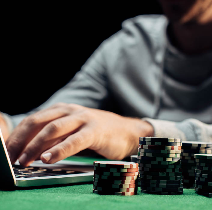 Player using his computer next to poker chips